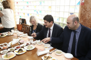 Three people sit at a table with several plates of food lined up in front of them.