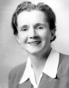 Black and white photo of a young white woman wearing a white collared shirt with a blazer over top