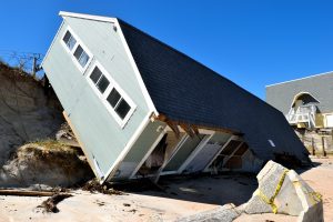 A house is knocked off its foundation and lying on the side of a damaged bank