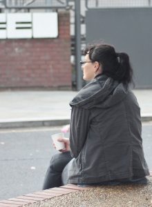 Young woman with coffee sitting outdoors in a contemplative pose.