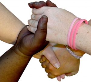 Four linked hands of various skin tones.