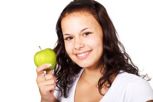 A person holding an apple and smiling.