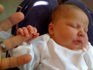 A mother is holding her baby's hand with her finger.