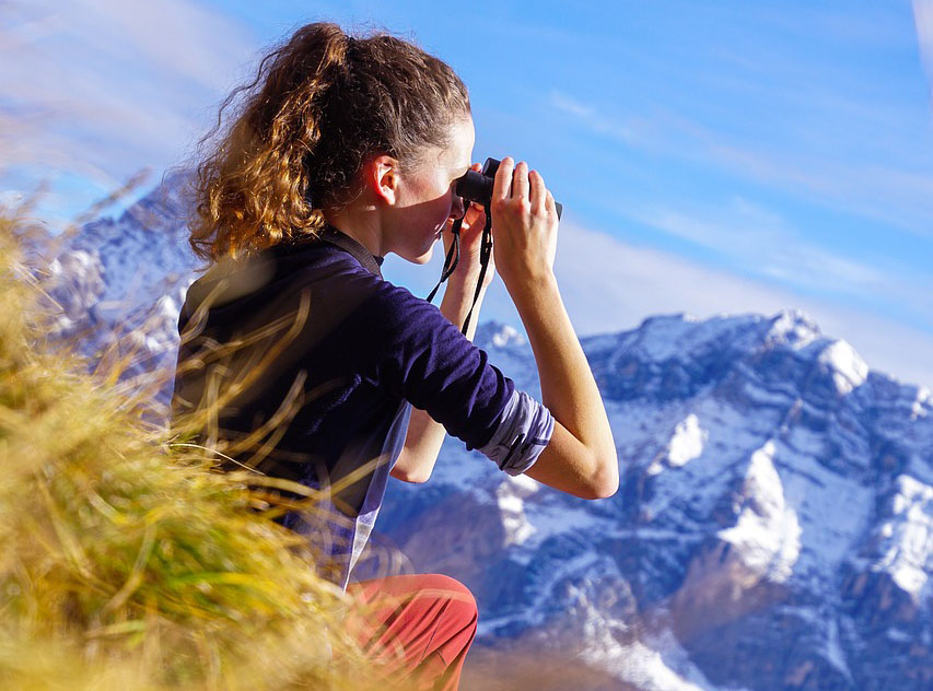 Woman exploring outside with binoculars.