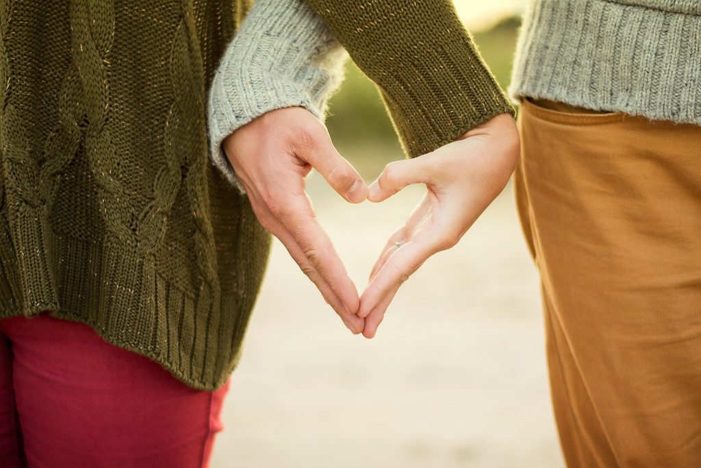 Couple making heart hand sign.