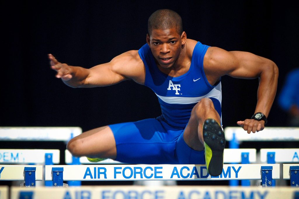 Man jumping over a track hurdle.