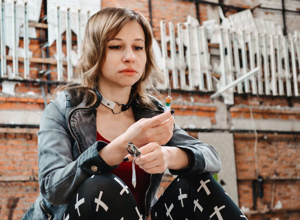 Woman holding syringe about to inject herself.