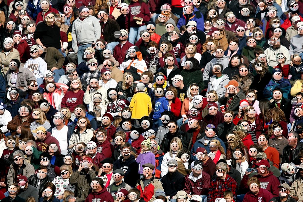 Large crowd with emoticon masks on their faces.